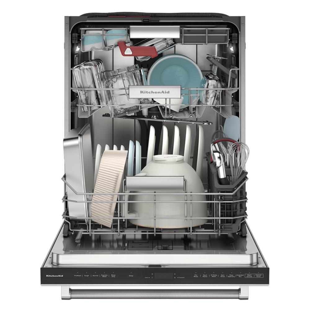 Open dishwasher loaded with various plates, bakeware, utensils, and glassware in KitchenAid appliance collection