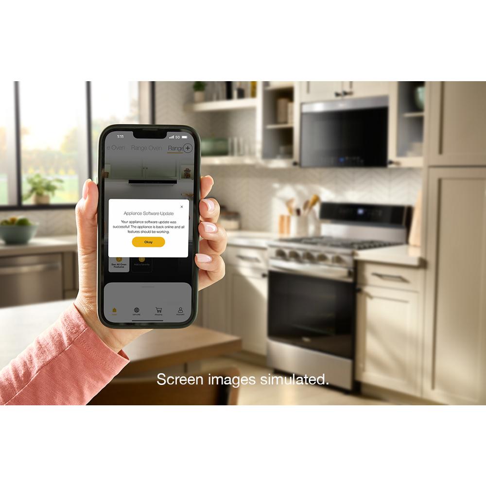Hand holding smartphone showing appliance software update with smart gas range in modern kitchen background