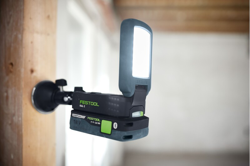 Compact black and green magnetic base with adjustable mount securing a Festool SysLite to wooden beam in tool accessories collection