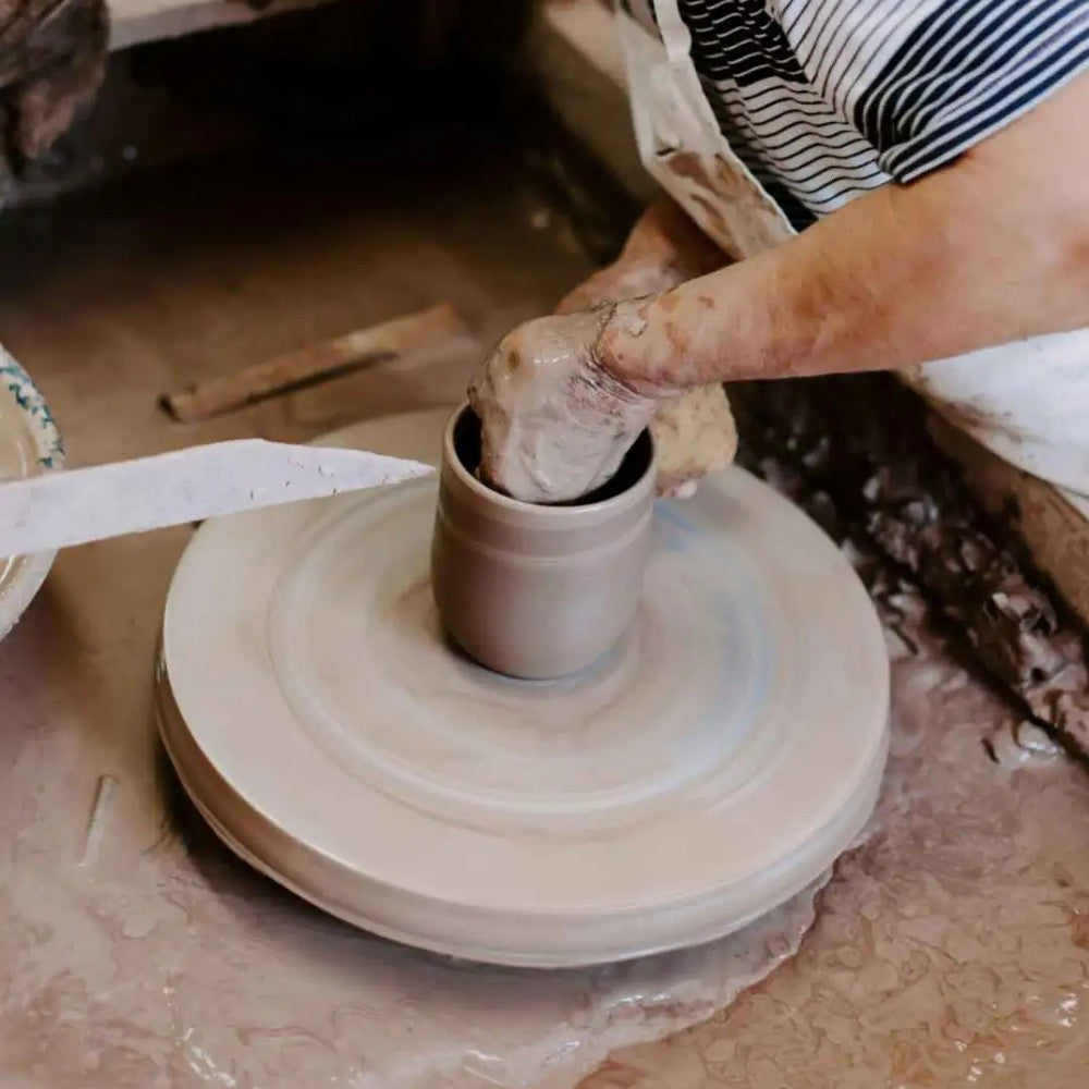 Close-up of artisan shaping clay on potter’s wheel in a rustic pottery studio setting