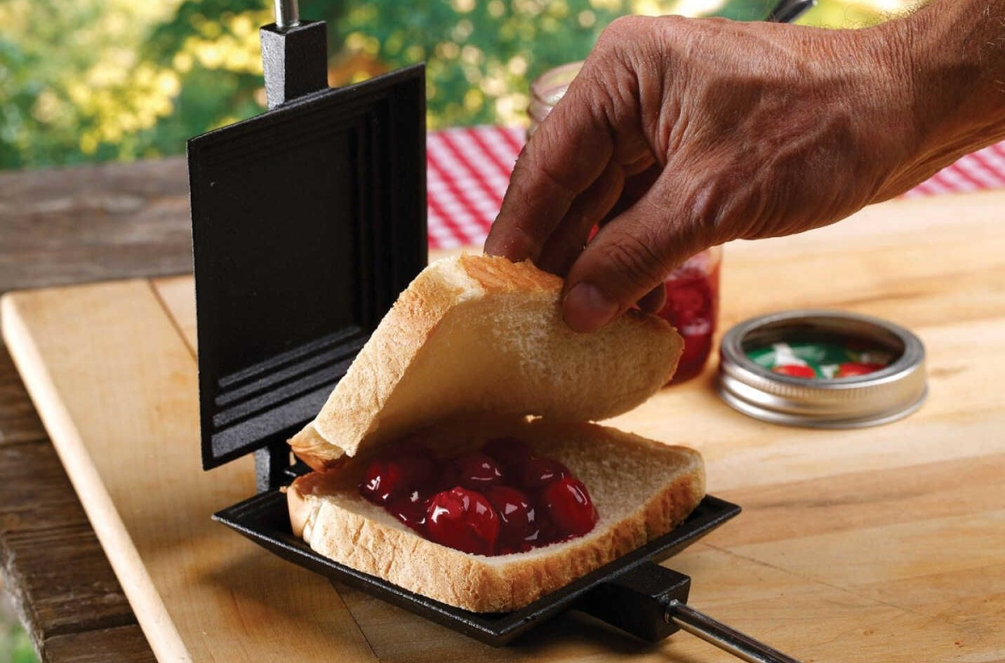 Cast iron pie cooker with 27-inch handle preparing cherry pie filling sandwich for grilling and outdoor kitchen use