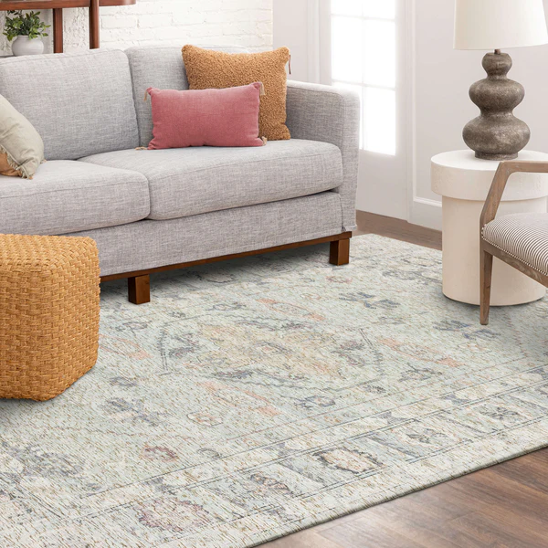 Light teal area rug with subtle faded floral and geometric motifs in a modern living room setting