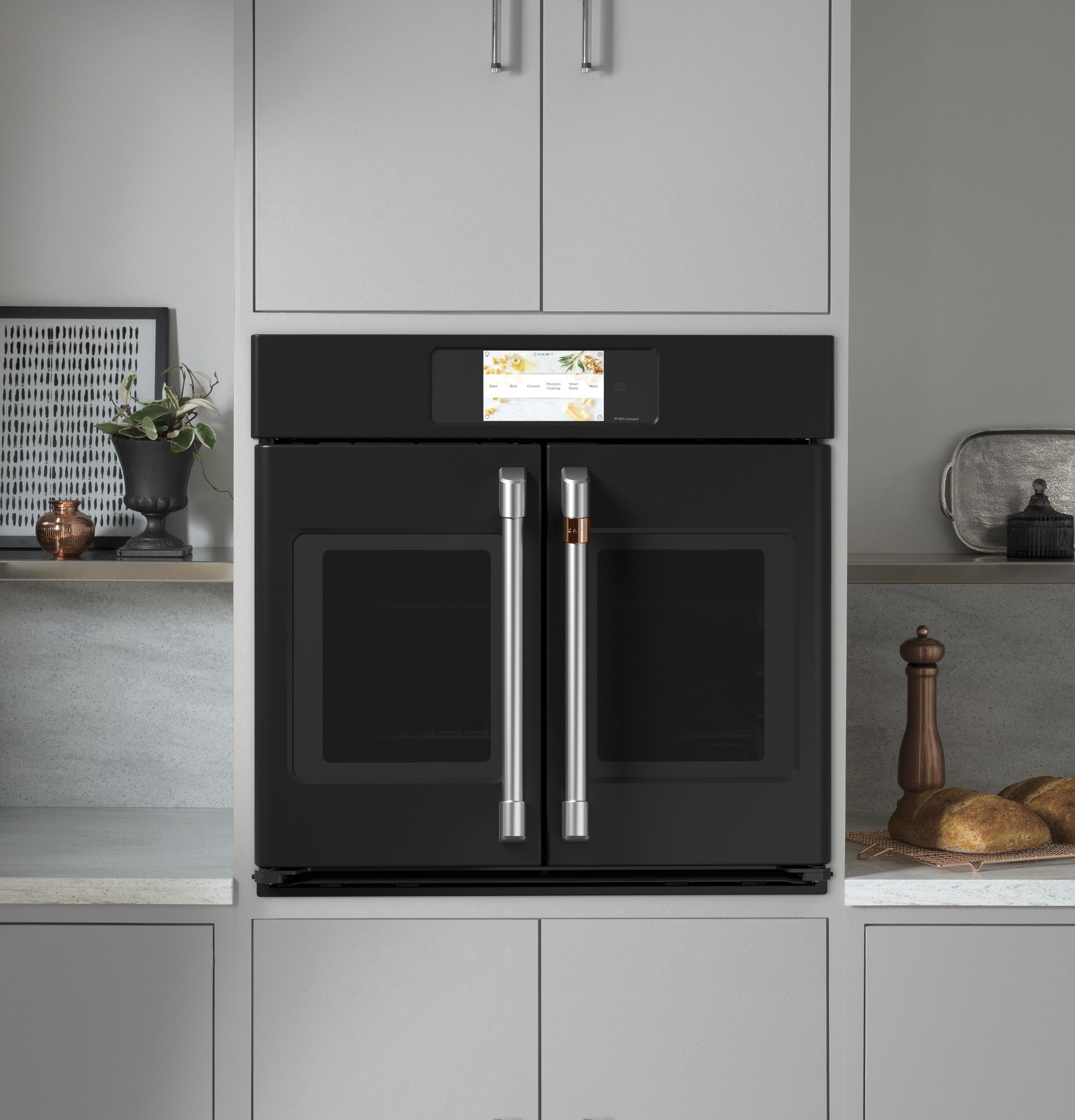 Modern black built-in convection wall oven with stainless steel French-style handles and digital touchscreen control panel