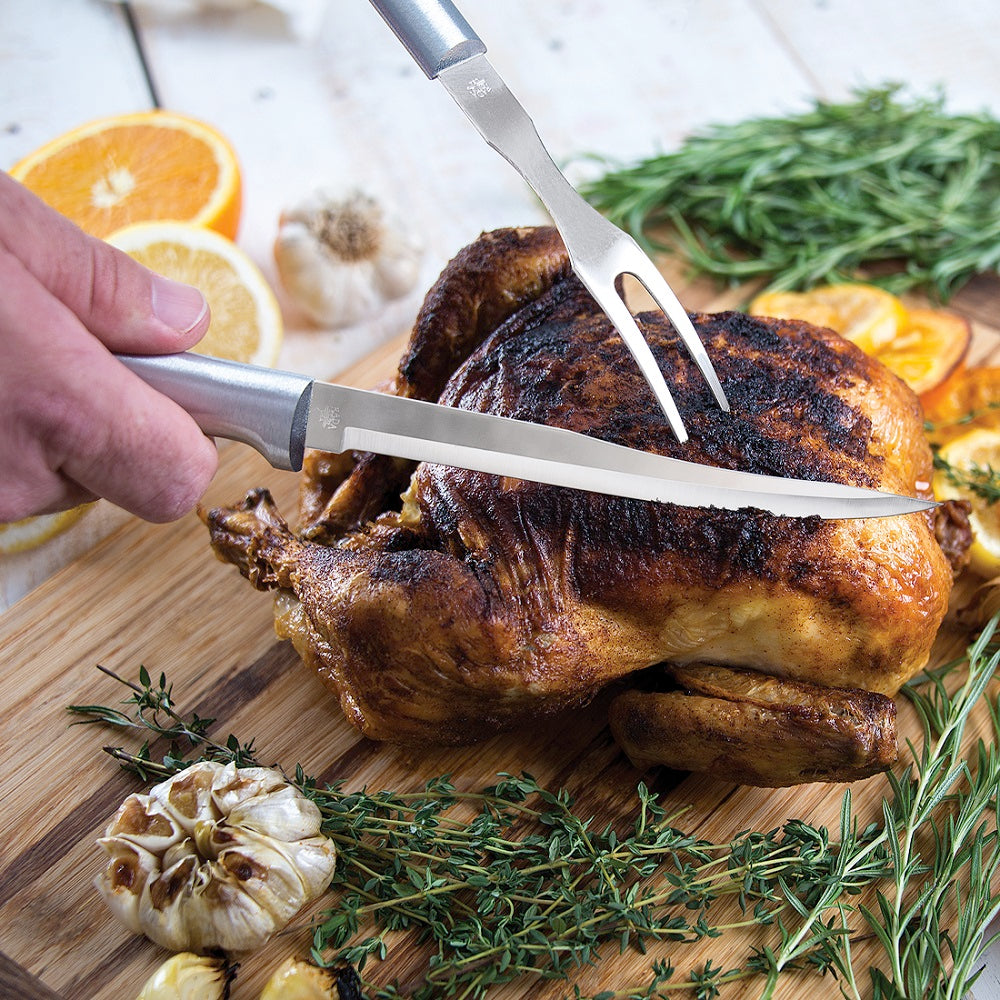 Stainless steel serrated steak knife with solid aluminum handle slicing roasted whole chicken on wooden board with fresh herbs, garlic, and citrus, ideal for Kitchenware and Cooking Utensils under $50.