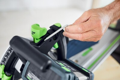Hand tightening a green and black Festool guide rail connector with a hex key for woodworking tool accessories assembly