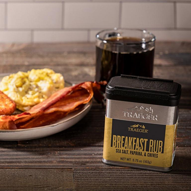 Metal container of Traeger Breakfast Rub with sea salt, paprika, and chives beside breakfast plate and coffee under $50 collection