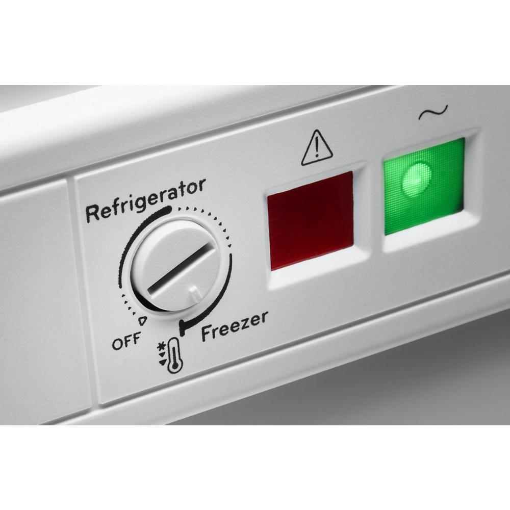 Close-up of a white appliance control panel with temperature dial, warning indicator, and green power light from Freezers collection