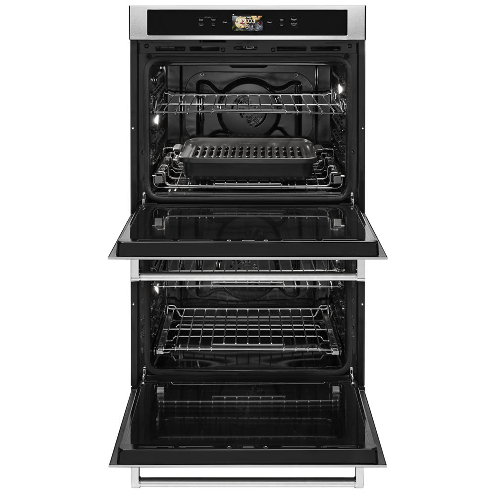 Open double wall oven with grill pan on middle rack and wire racks inside stainless steel kitchen appliance