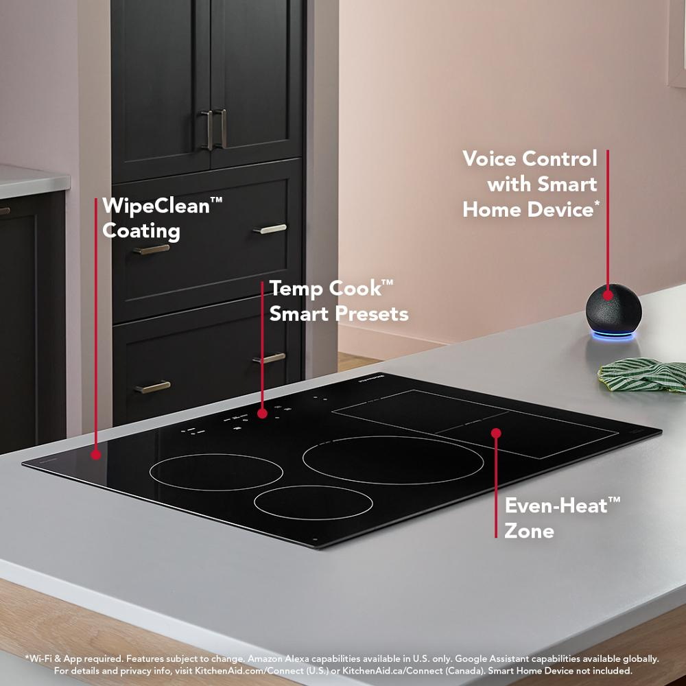 Black glass induction cooktop with smart presets, even-heat zones, wipe-clean surface, and voice control device on countertop
