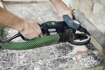 Hands guiding Festool diamond grinder with dust extraction smoothing tile surface during home improvement project
