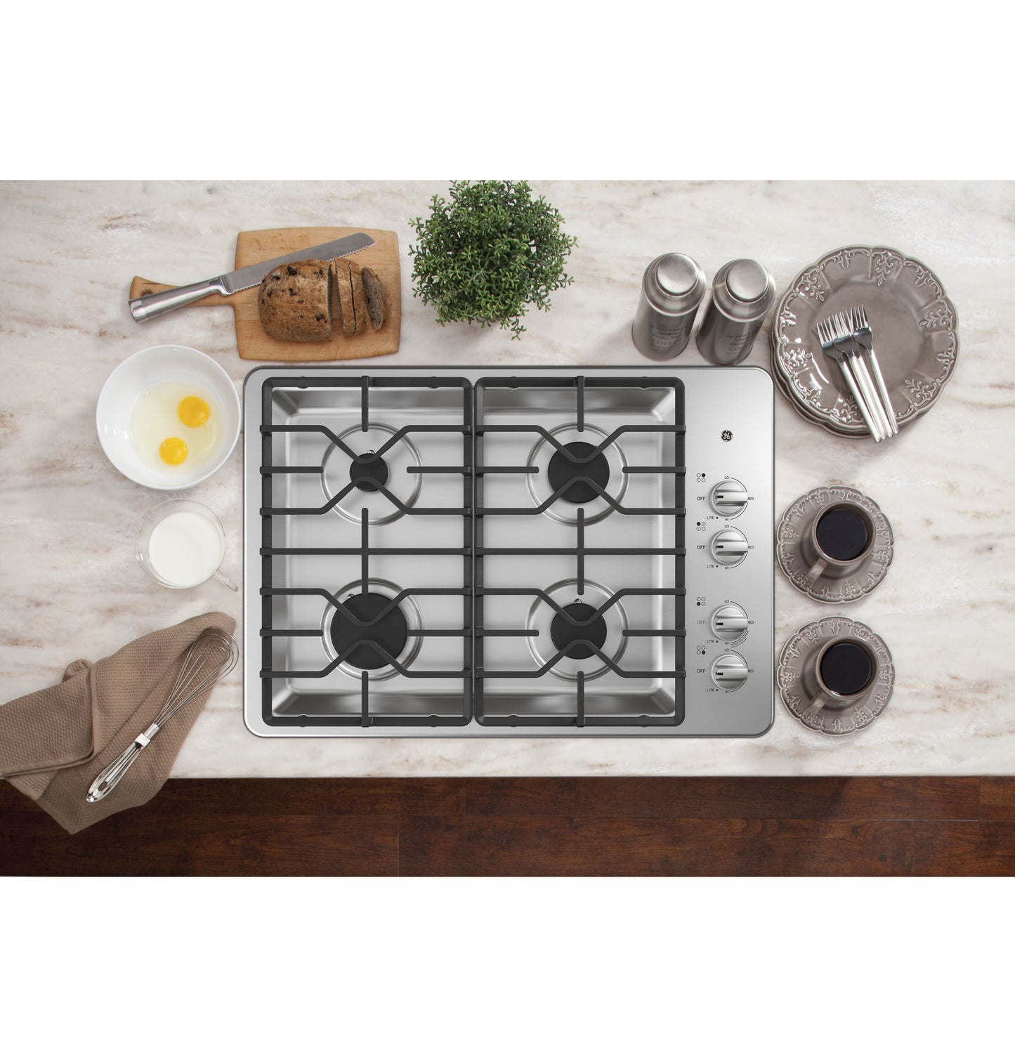 Stainless steel built-in gas cooktop with four burners and dishwasher-safe grates in a kitchen setting from Cooktops collection