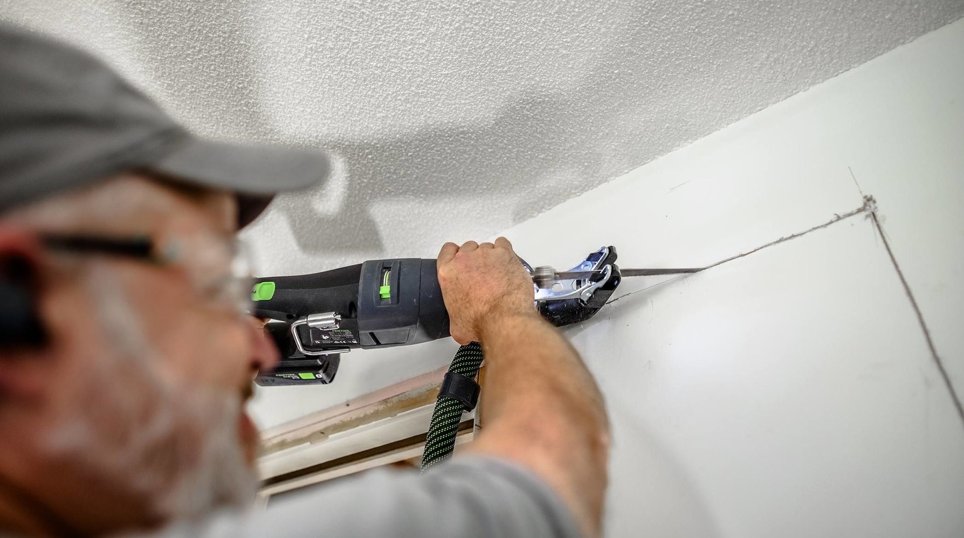 Person using cordless reciprocating saw from Festool cordless tools collection to cut drywall in home improvement project