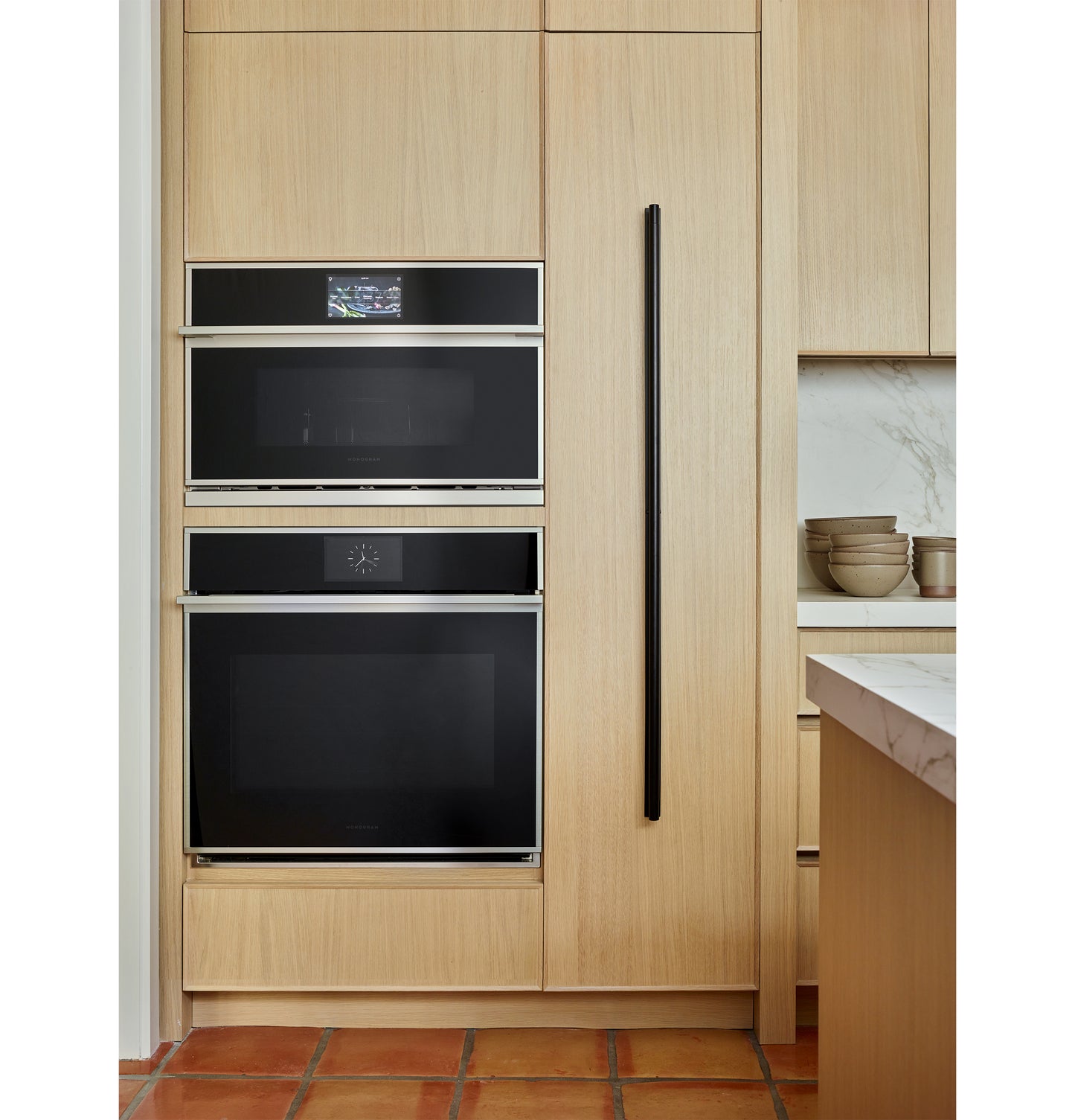Built-in minimalist wall oven and microwave with black glass and stainless steel trim in modern kitchen setting