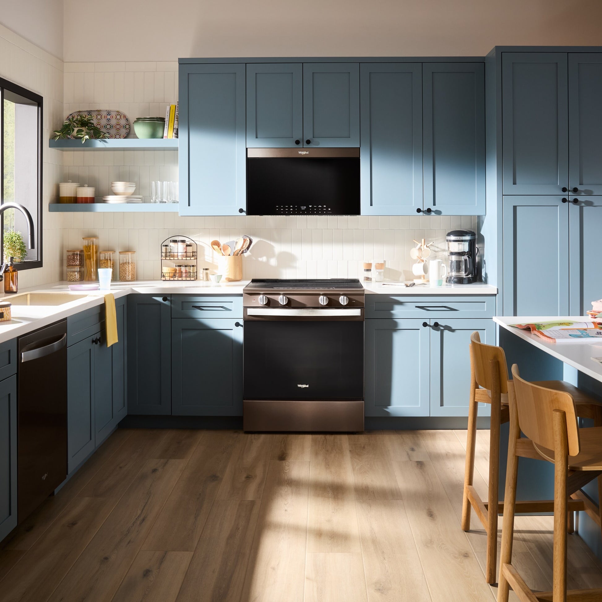 Modern kitchen featuring blue cabinetry with black air fry over-the-range microwave and stainless steel electric range appliances