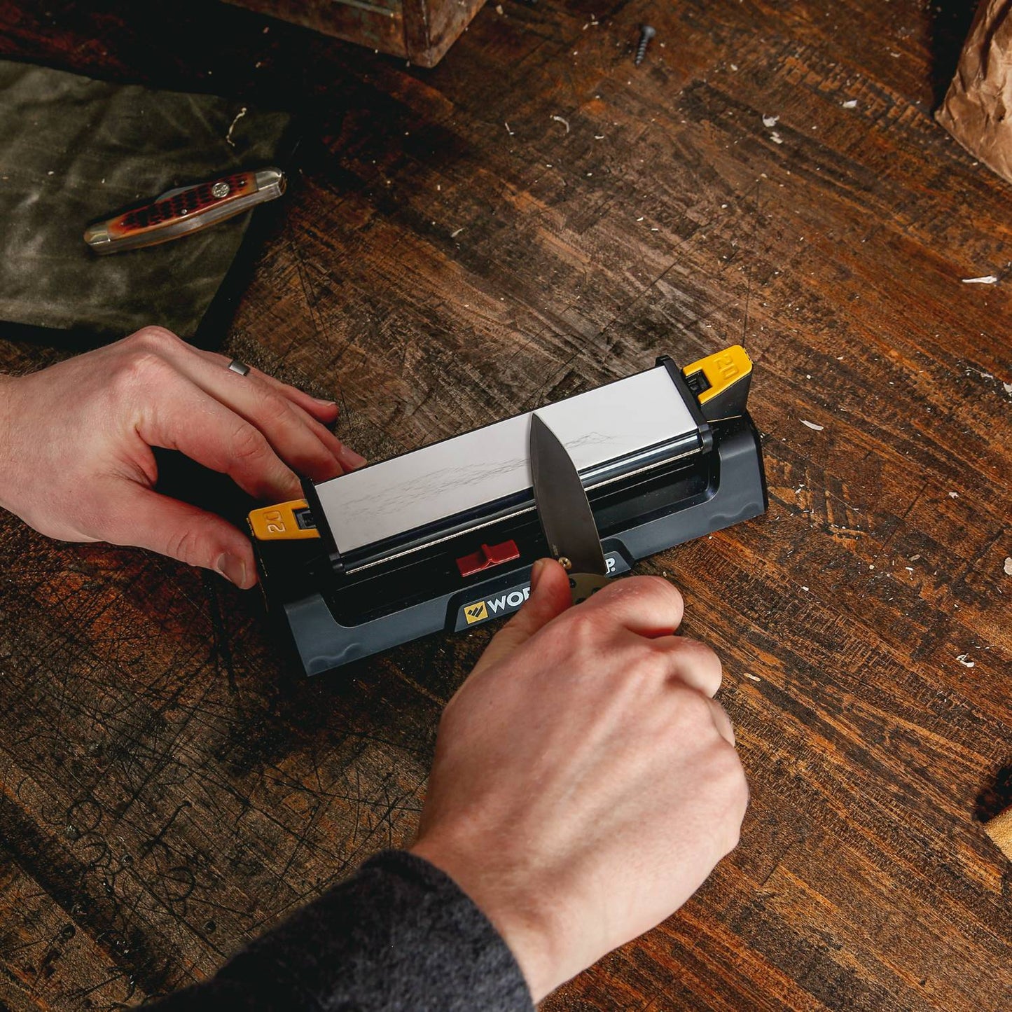 Person using a Work Sharp Benchstone sharpener on a knife for kitchenware and woodworking tools maintenance