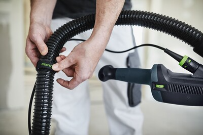 Hands fastening a Festool-branded hose clip to a black corrugated hose on a power tool in a workshop setting