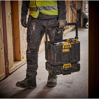 Worker carrying black and yellow DEWALT Toughsystem storage box with adjustable work light on construction site
