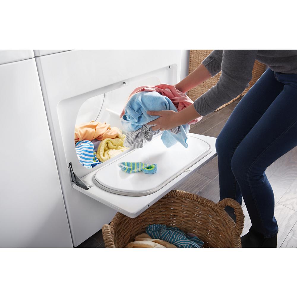 Person unloading a white front load dryer into a woven laundry basket in a home laundry room setting