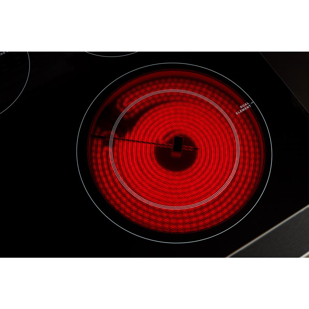Close-up of electric ceramic glass cooktop burner glowing red during heating cycle in modern kitchen setting