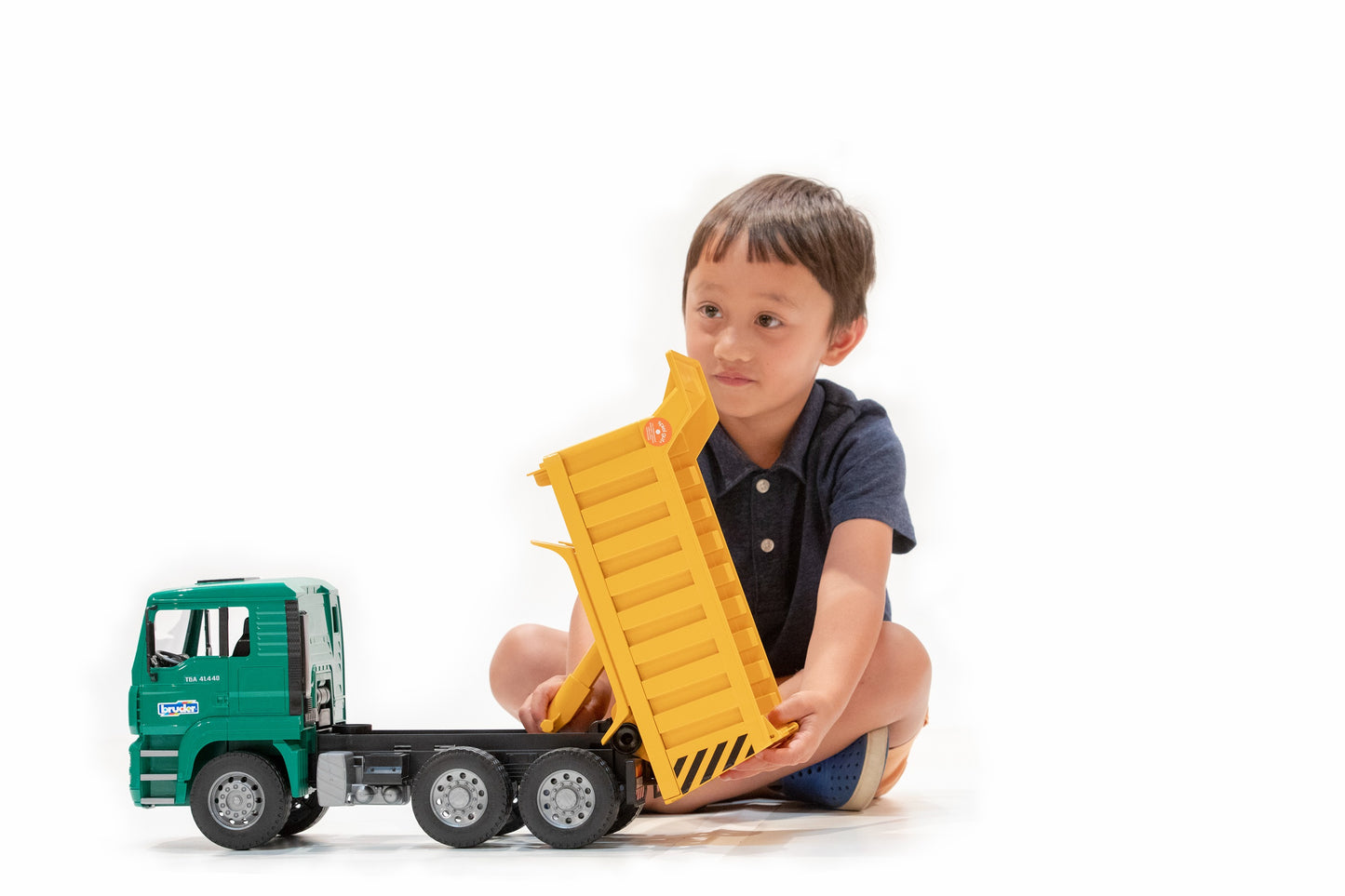 Child playing with Bruder truck toy featuring detailed tipping yellow bed in Vehicles & Remote Controlled Toys collection