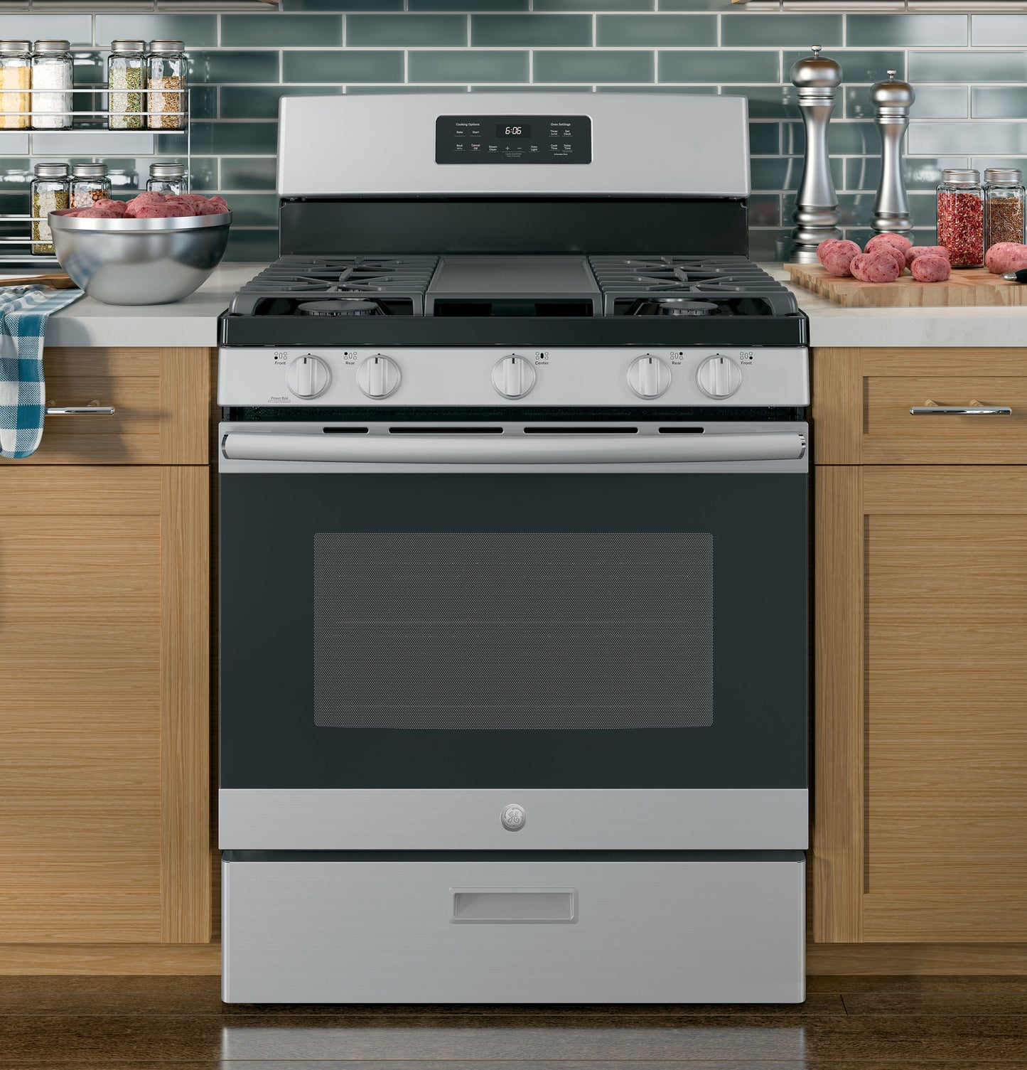 Stainless steel freestanding gas range with five control knobs and digital display in modern kitchen setting