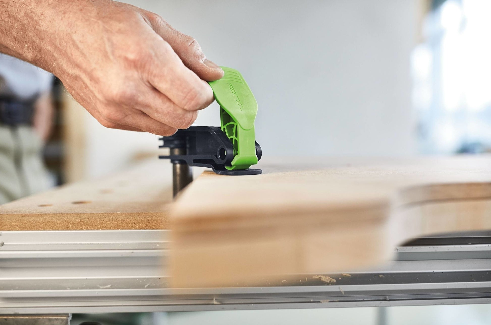 Hand securing green lever on Festool quick clamp used in woodworking and home improvement projects