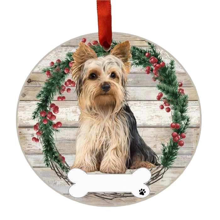 Round Christmas ornament featuring a Yorkie dog inside a holly wreath with red berries and wood plank background
