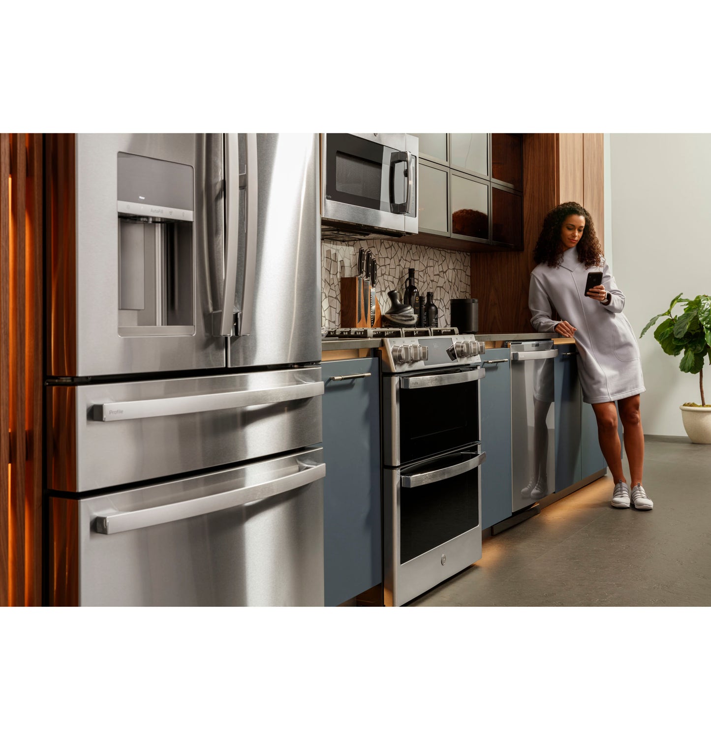 Modern kitchen with stainless steel refrigerator, double oven gas range, dishwasher, and blue lower cabinets from Ranges collection