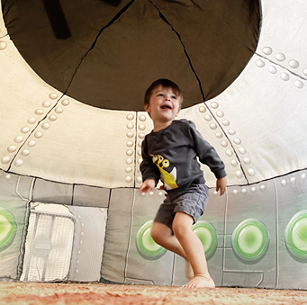 Child playing inside beige fabric UFO-shaped AirFort for pretend play in toys and games collection under $100