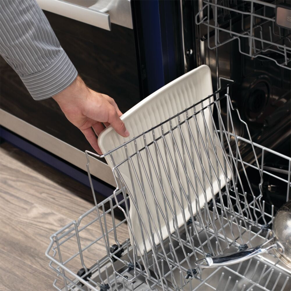 Hand placing a white ceramic drip tray into an open dishwasher rack for kitchenware cleaning in home appliances collection