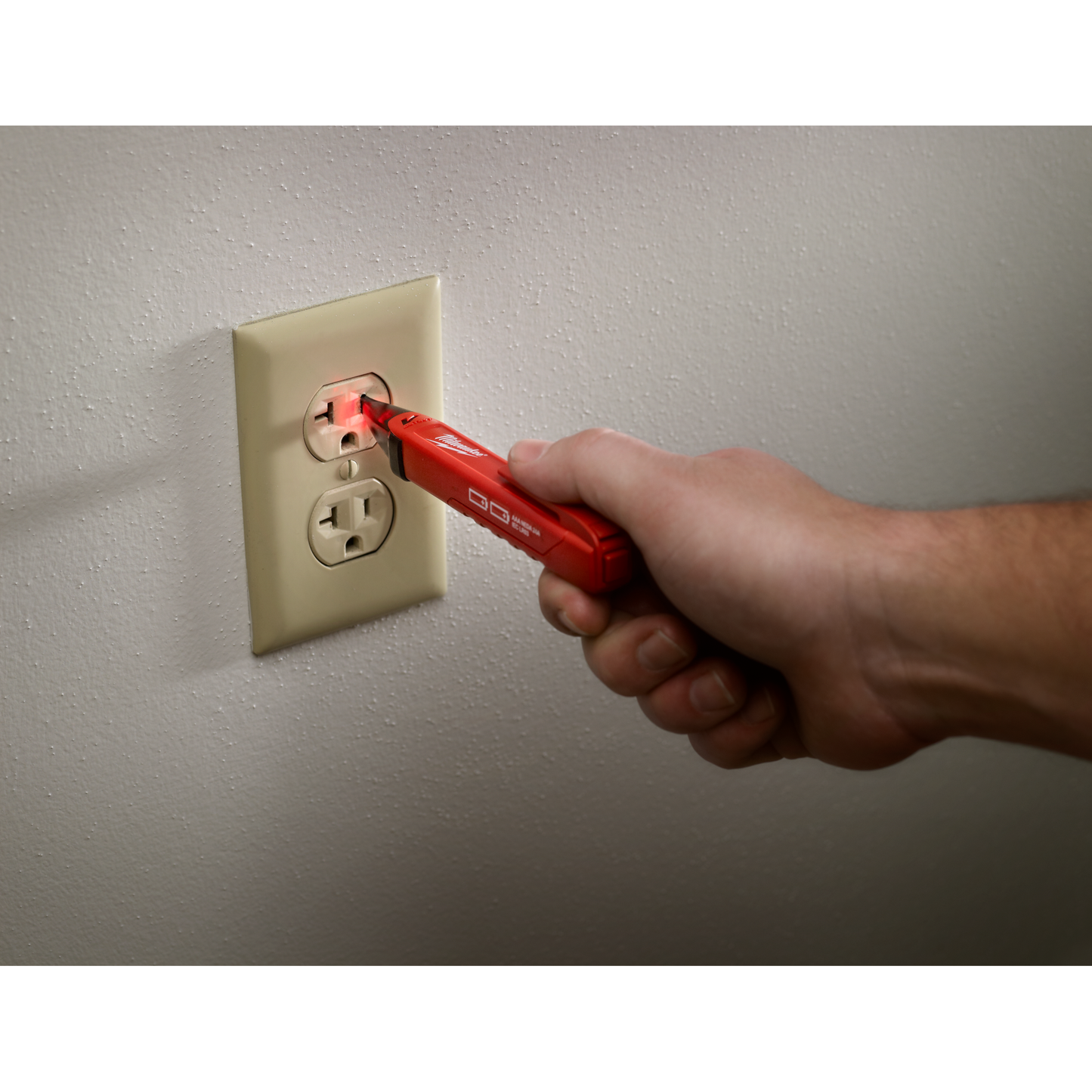 Handheld red voltage detector testing electrical outlet with glowing tip for home improvement and tools use