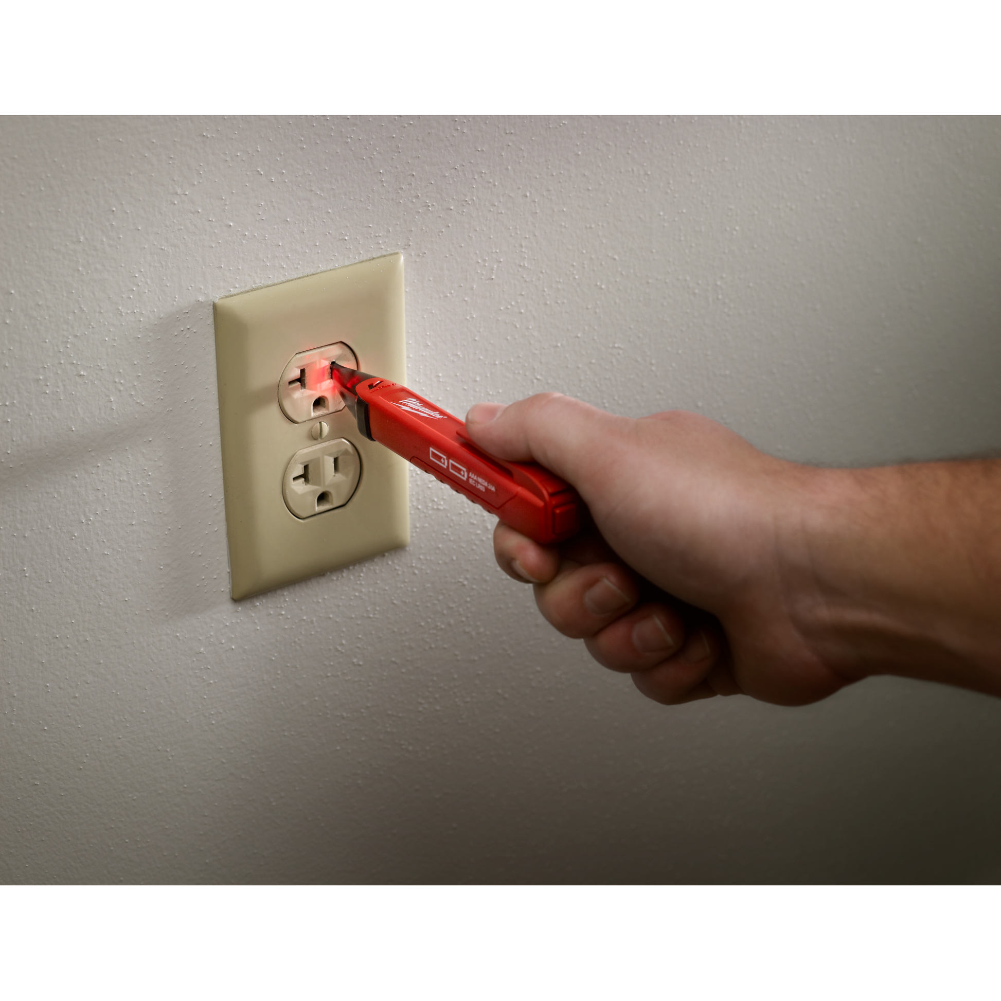 Handheld red voltage detector testing electrical outlet with glowing tip for home improvement and tools use