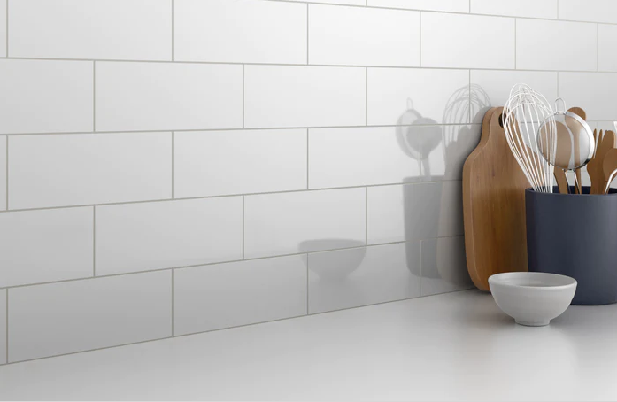 Glossy white glazed ceramic wall tile backsplash in kitchen setting with utensils for home improvement projects