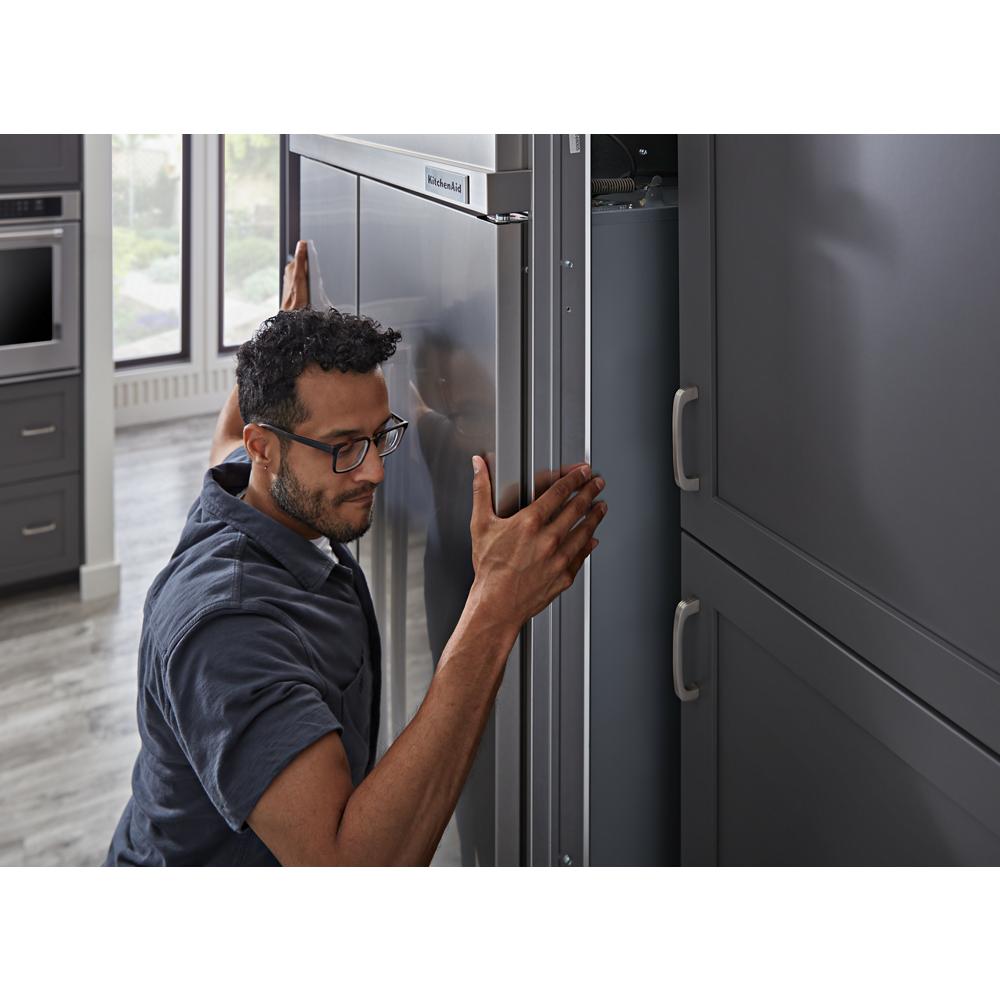Man installing stainless steel built-in side-by-side refrigerator with PrintShield finish in modern kitchen setting