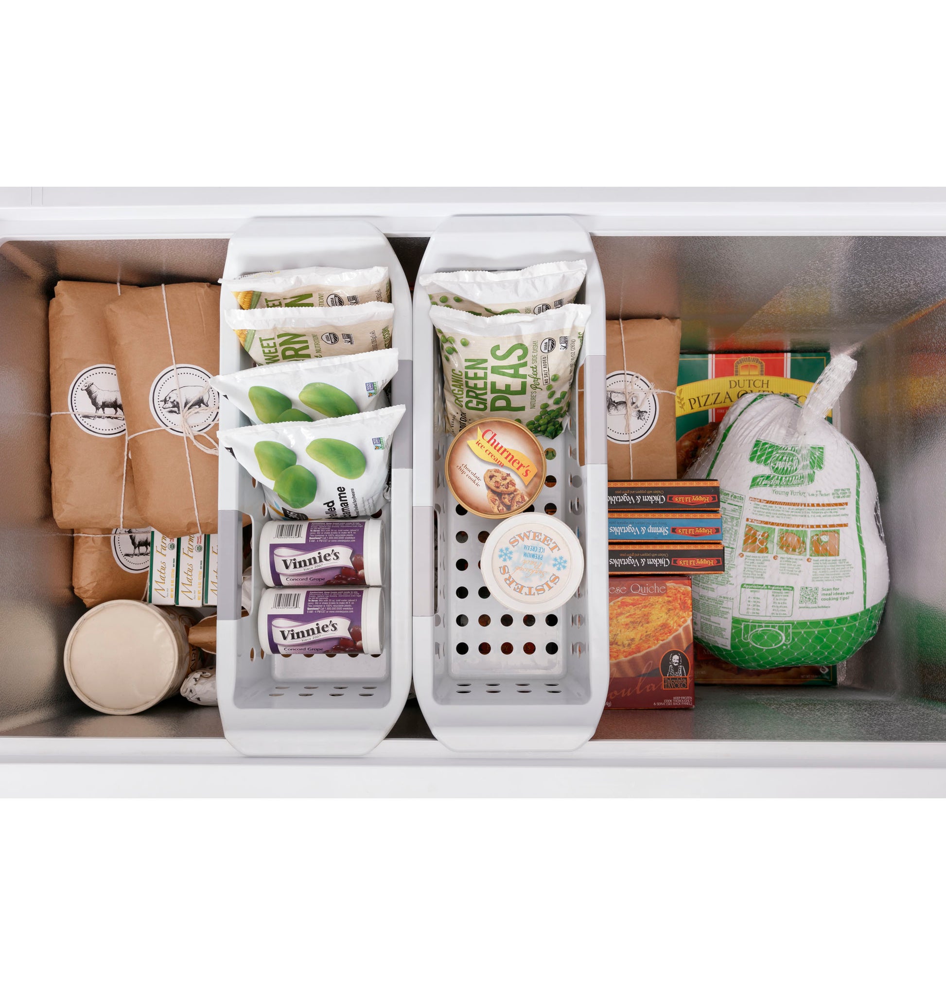 Top-down view of organized frozen food including vegetables, meat, and frozen meals inside white chest freezer baskets