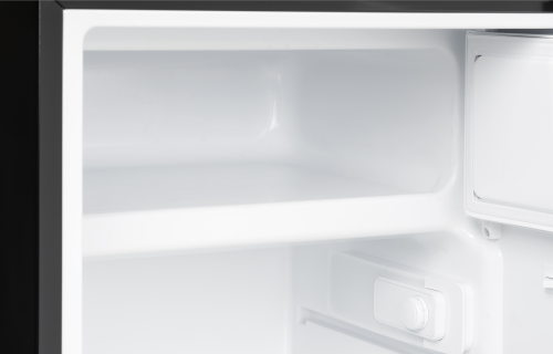 Interior of a compact refrigerator with true freezer compartment and adjustable white shelves for kitchen appliance collections