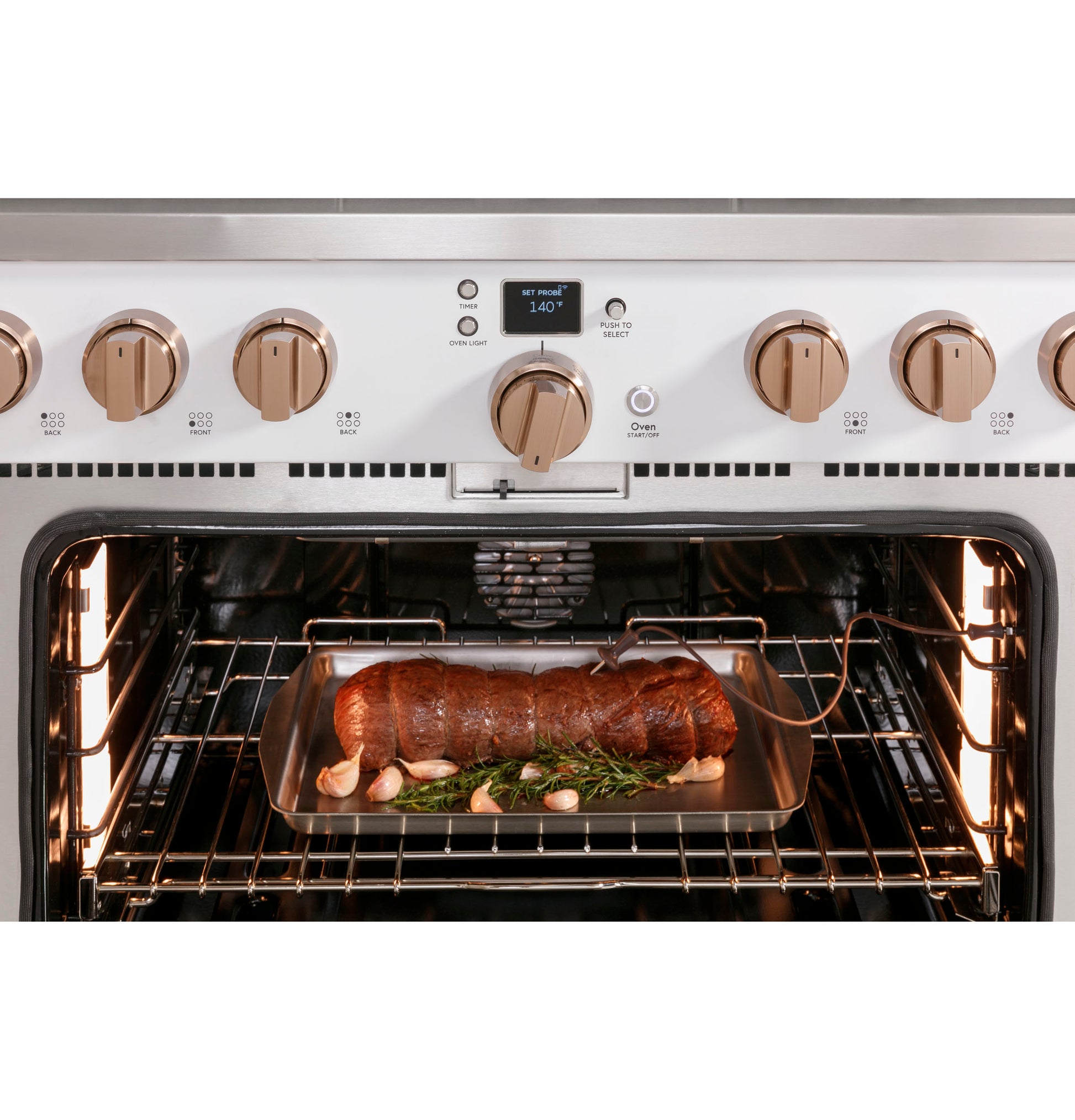 Open oven of white commercial-style gas range with six burners and roast cooking inside on a metal tray