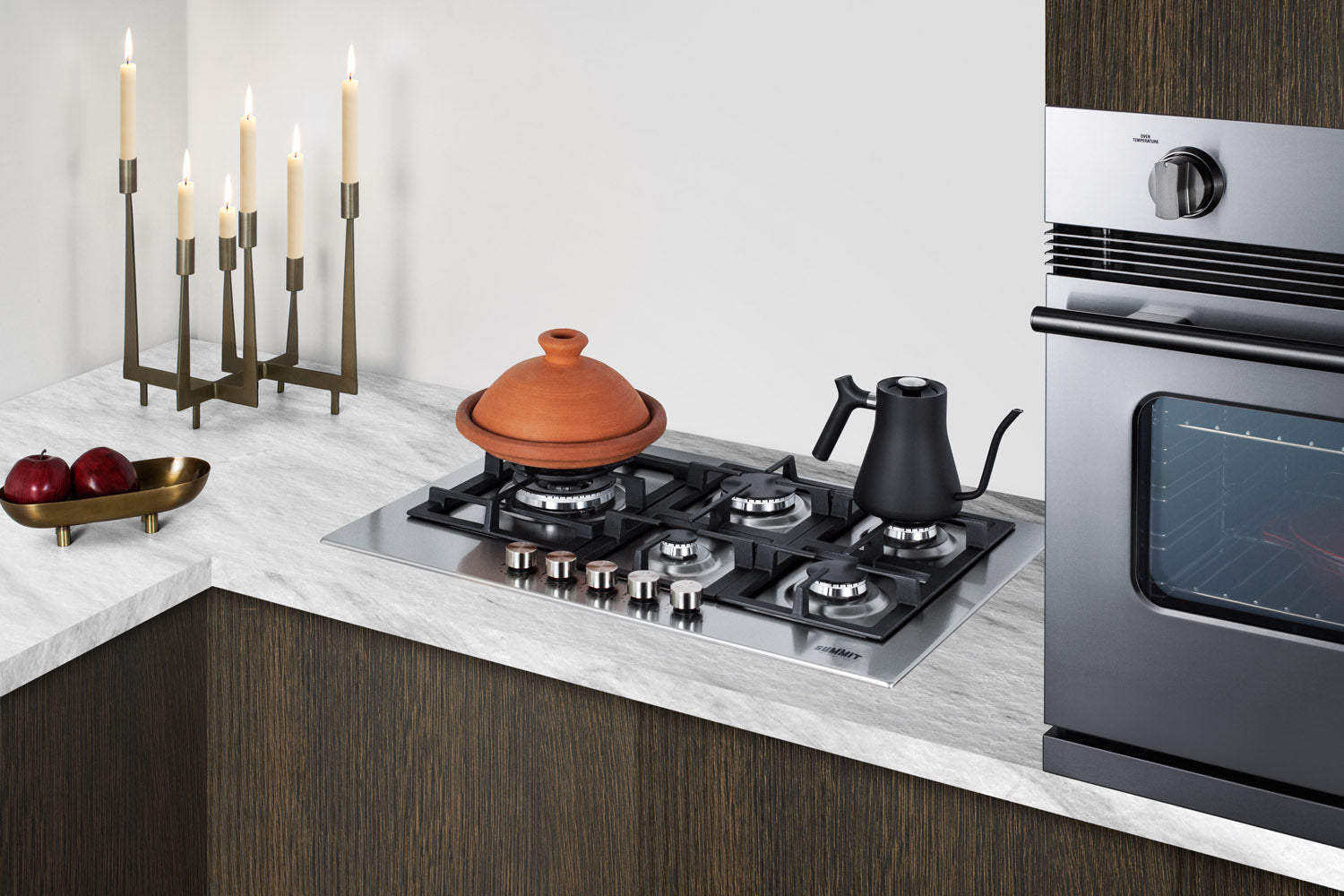 Modern stainless steel 24-inch four-burner propane gas cooktop installed in corner kitchen with countertop decor