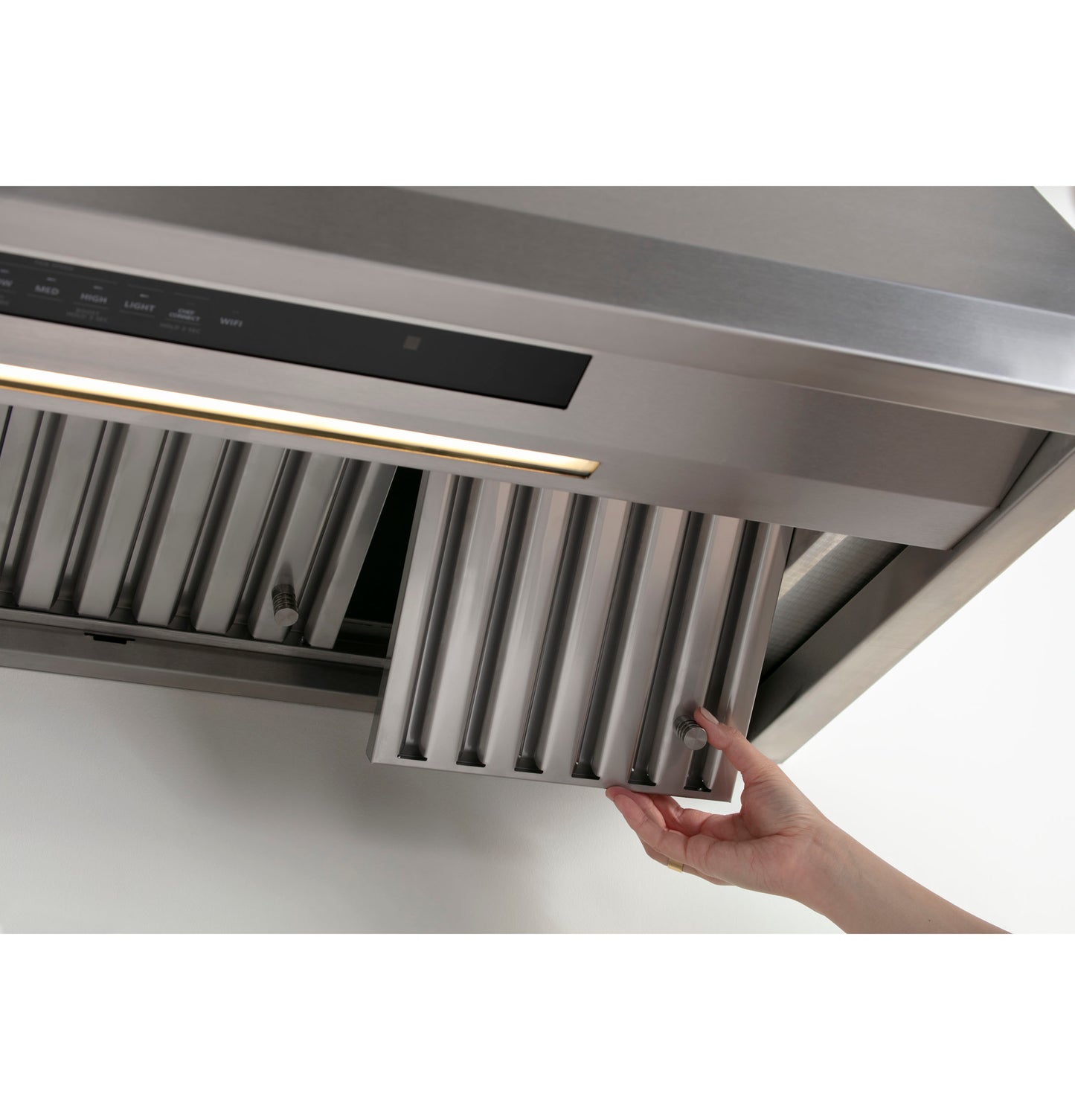 Hand removing stainless steel baffle filter from a modern professional kitchen hood in appliances and kitchenware collection
