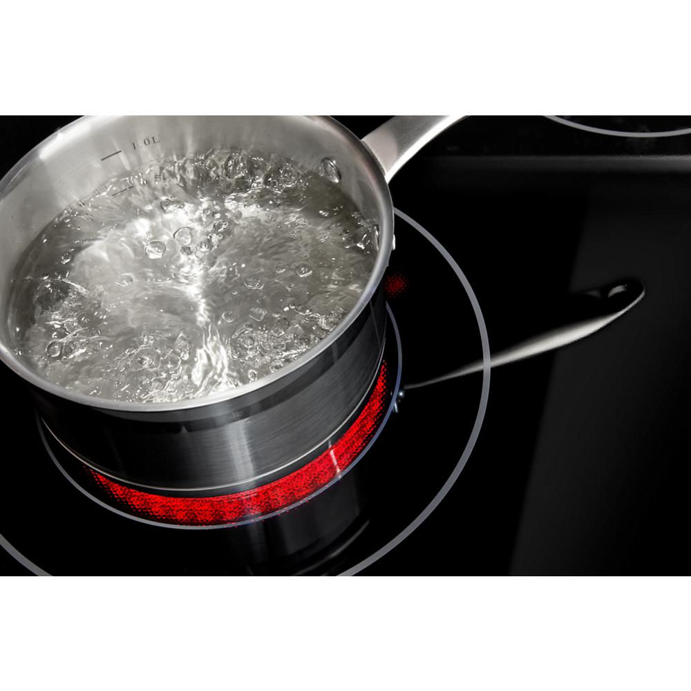 Stainless steel pot with boiling water on a glowing red element of a 30-inch electric range cooktop