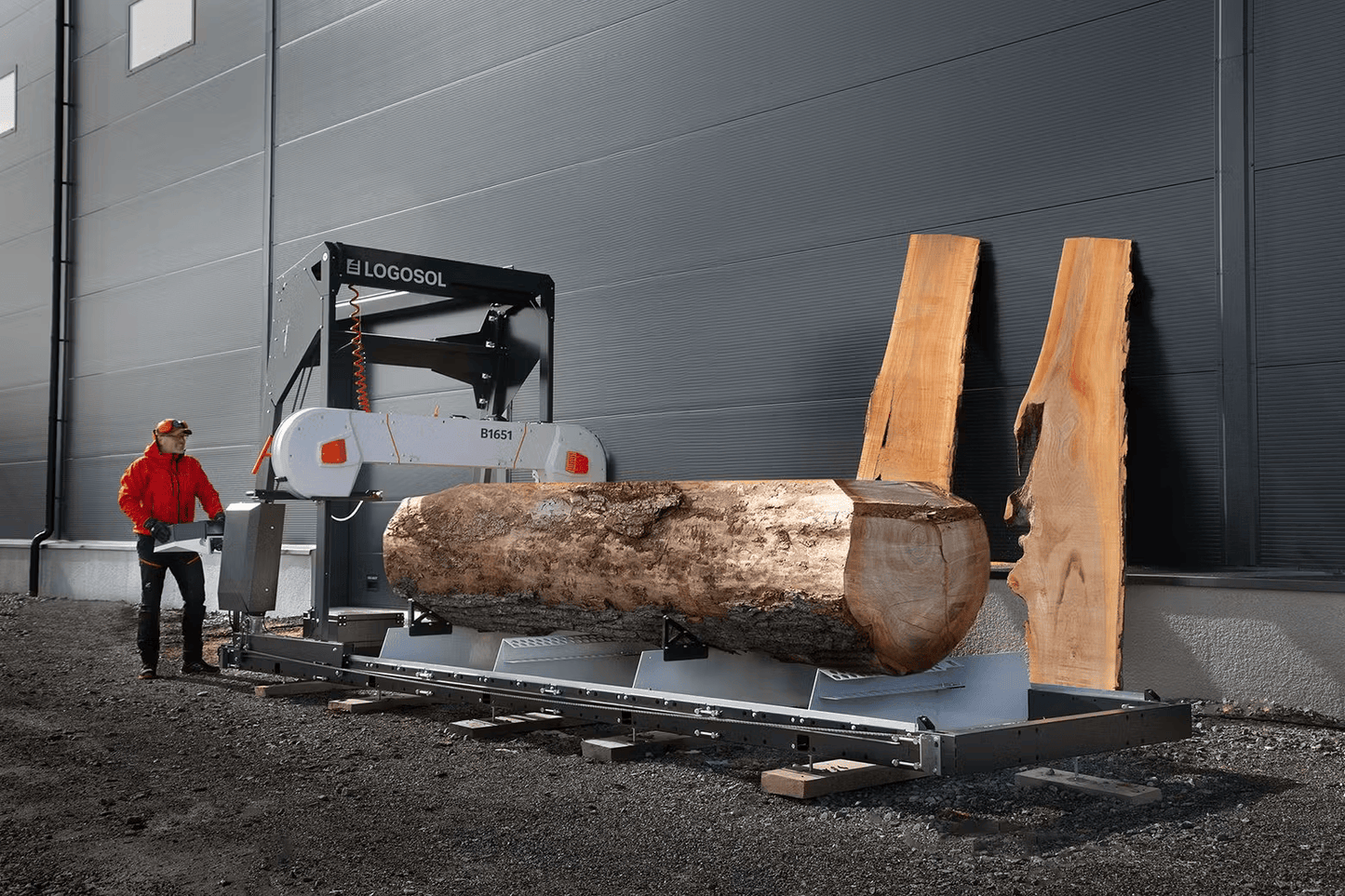 Industrial band sawmill cutting large log into slabs with operator managing controls for precise wood cutting
