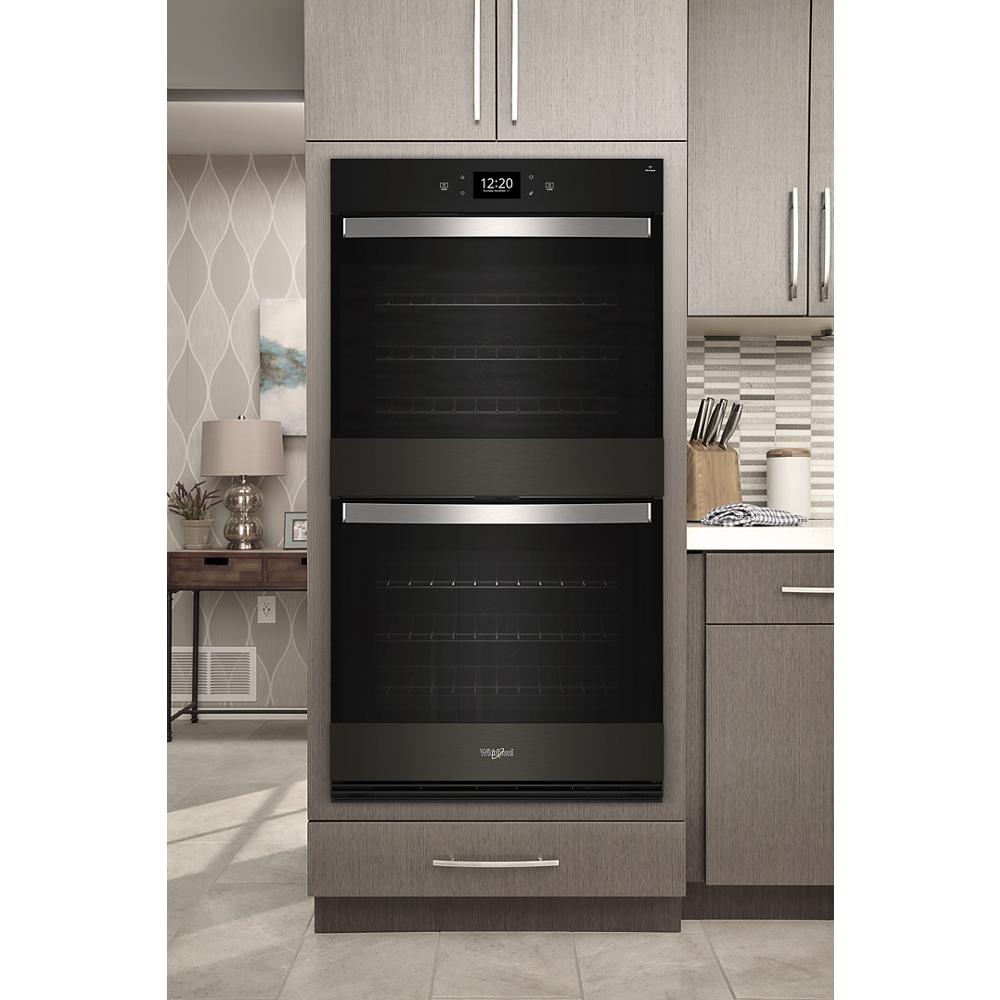 Built-in double wall oven in black with stainless steel handles, digital display, and modern kitchen cabinetry surroundings