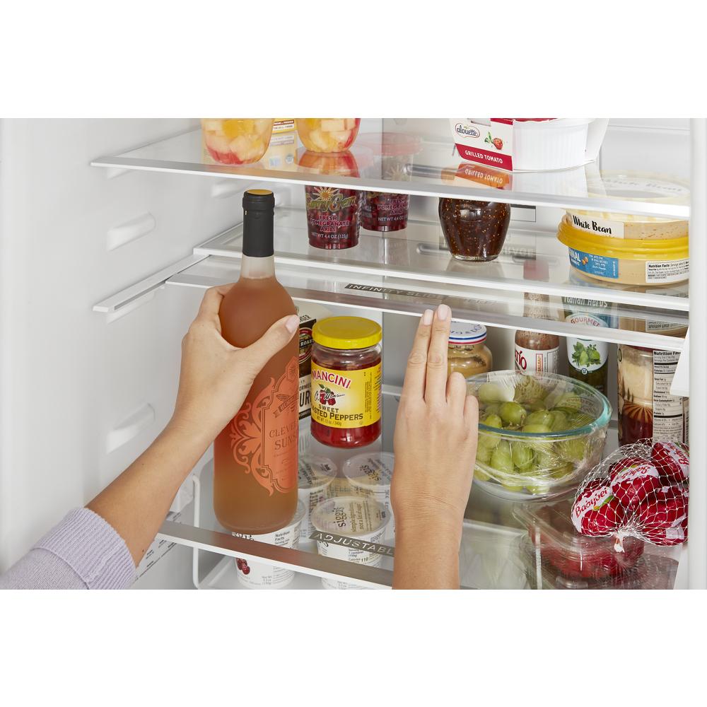 Hands organizing condiments and beverages inside a spacious refrigerator with clear glass shelves from appliance collection