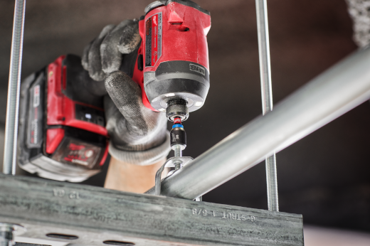 Red impact driver with magnetic nut driver attachment tightening metal conduit clamp in home improvement and tool accessories collection