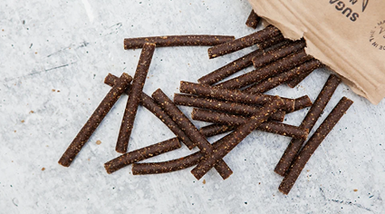 Dark brown natural beef stick dog treats spilled from a kraft paper bag in pet treats and supplies under $50 collection