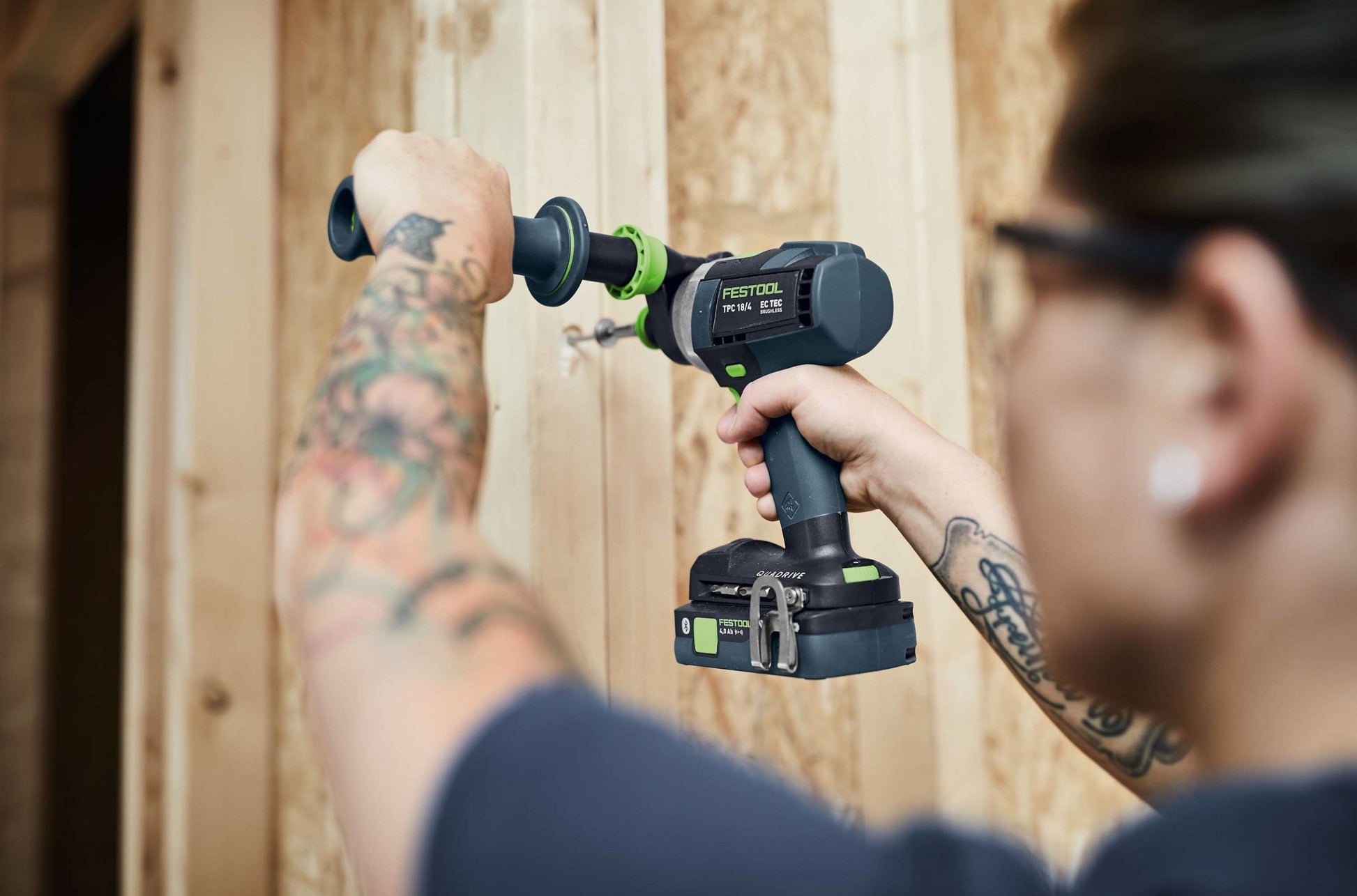 Person using Festool cordless hammer drill on wooden wall in woodworking and power tools setting