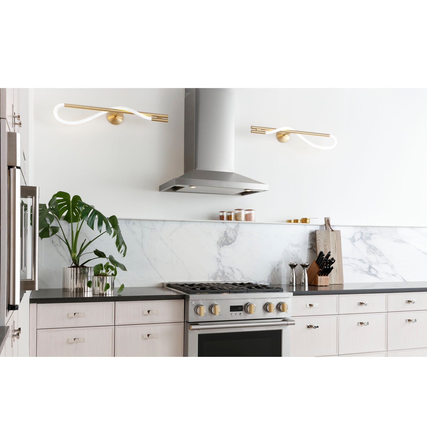 Gray wall-mounted vent hood above stainless steel gas range with marble backsplash in modern kitchen appliances setting