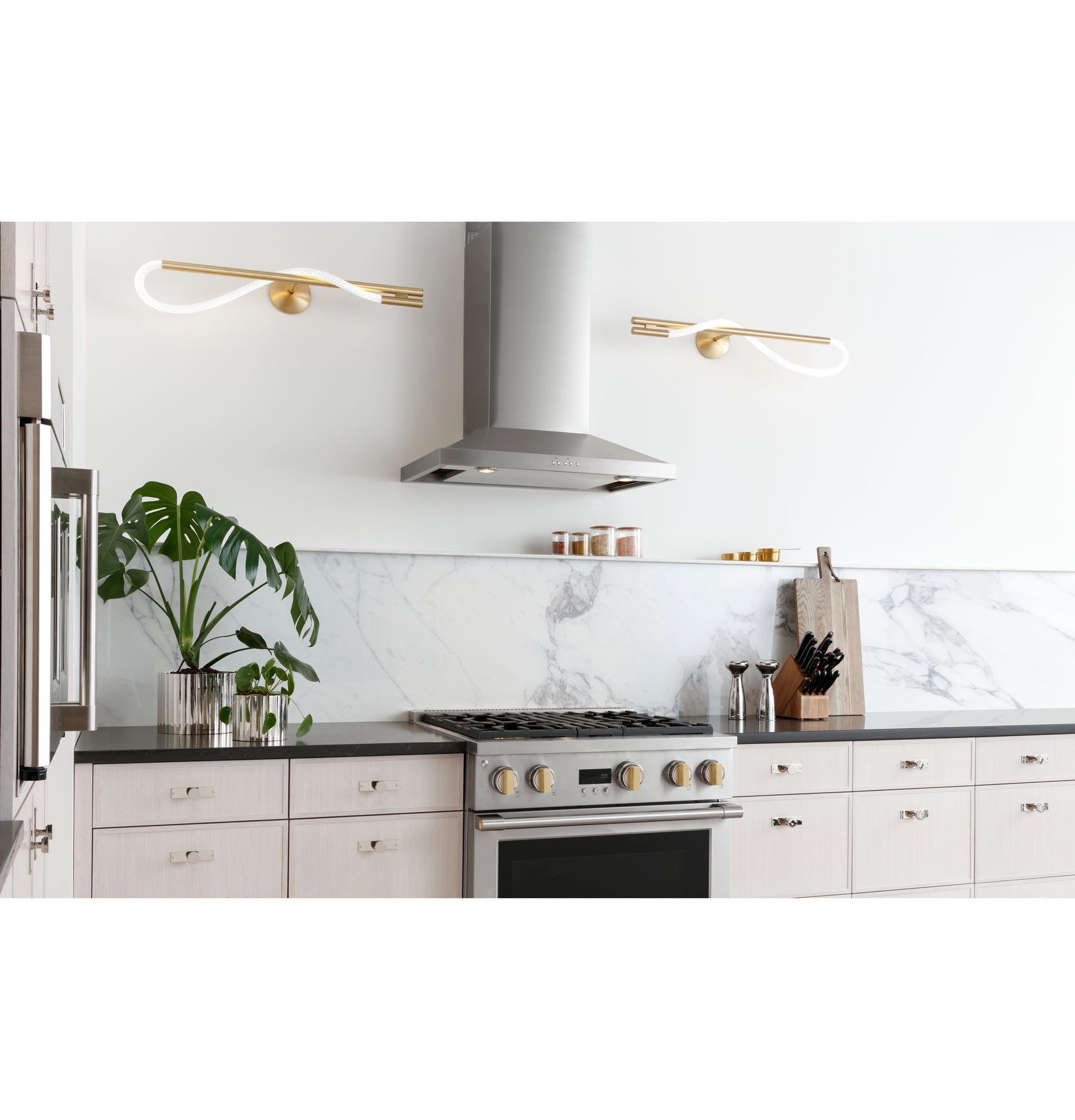 Gray wall-mounted vent hood above stainless steel gas range with marble backsplash in modern kitchen appliances setting