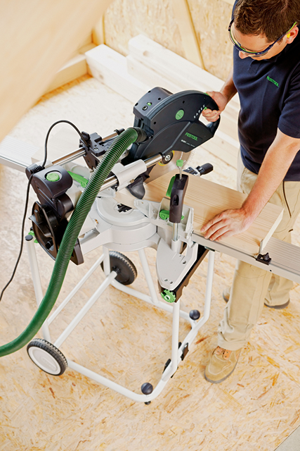 Person working with Festool sliding compound miter saw on wood piece in power tools and home improvement setting