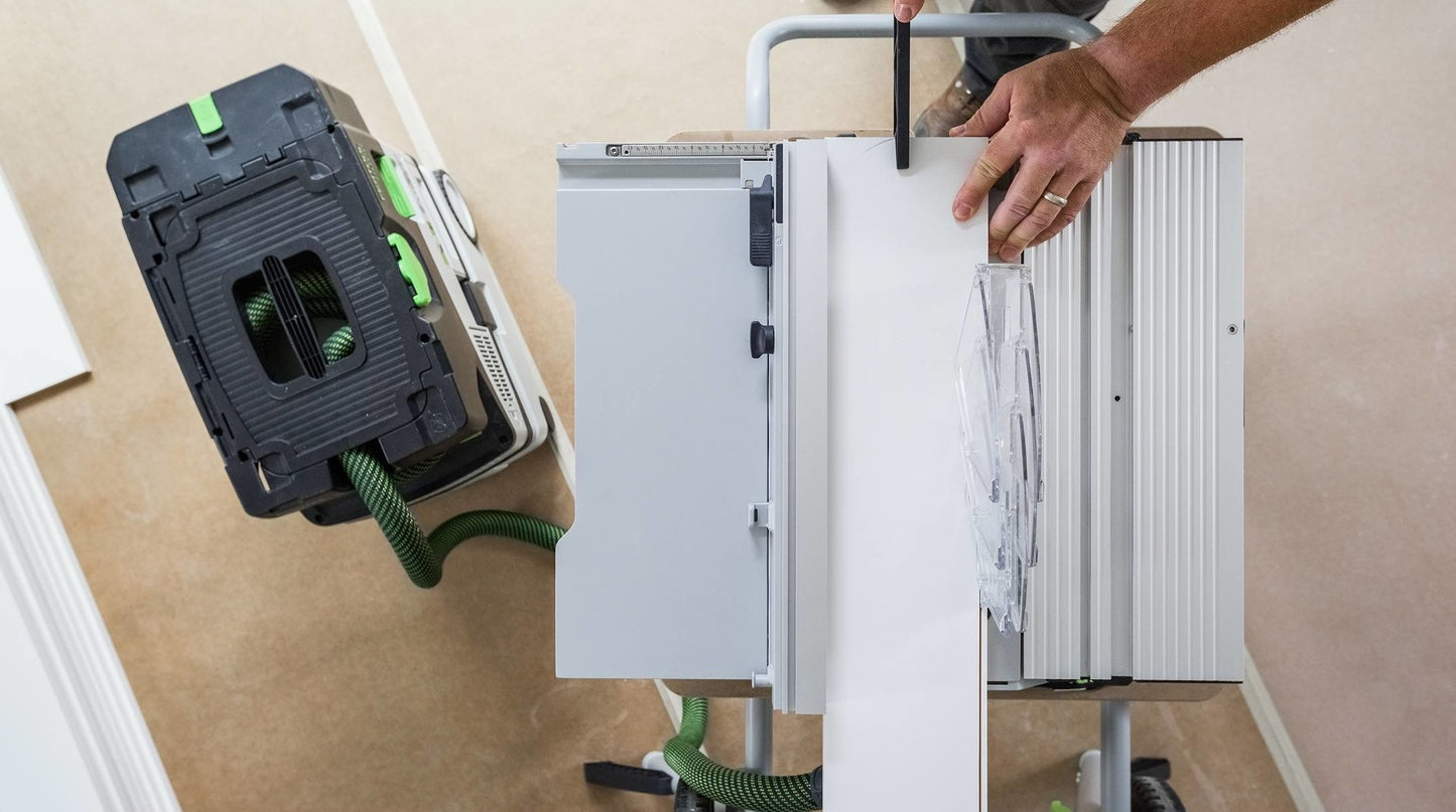 Top-down view of a person adjusting a compact Festool cordless table saw on a portable workbench in a workshop